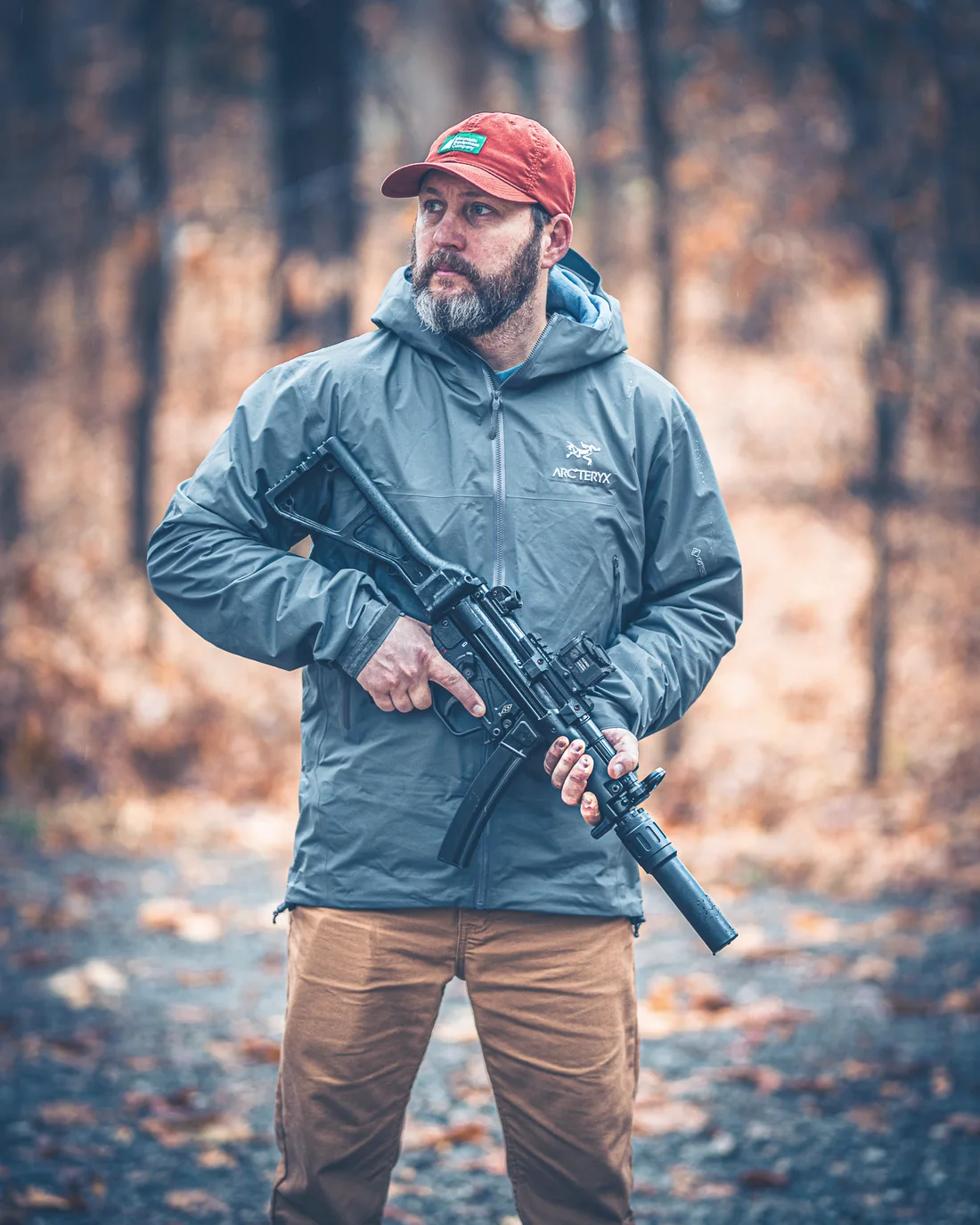Suppressed pistol-caliber carbine in hand in autumn woods