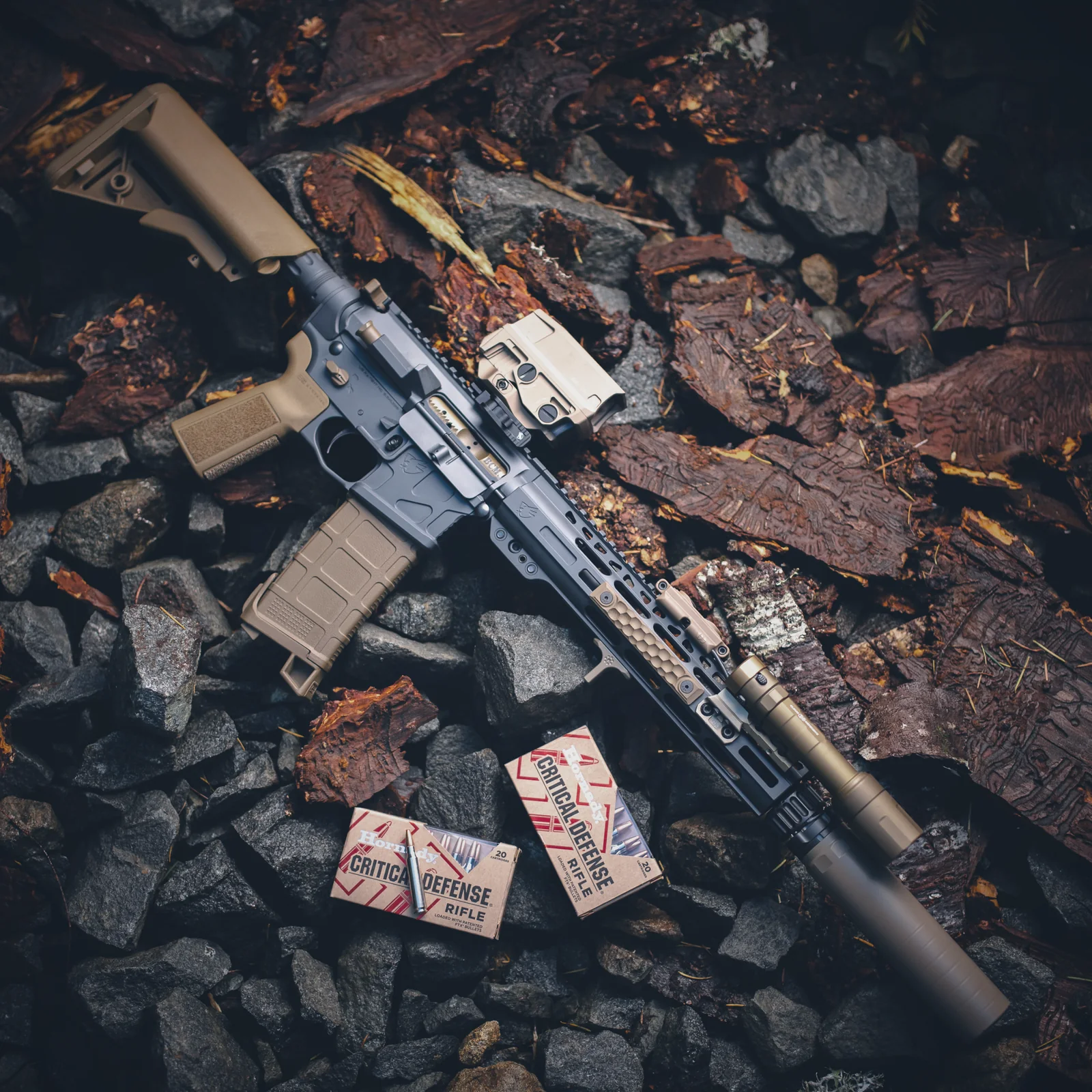 Suppressed rifle laid on wet stone and bark
