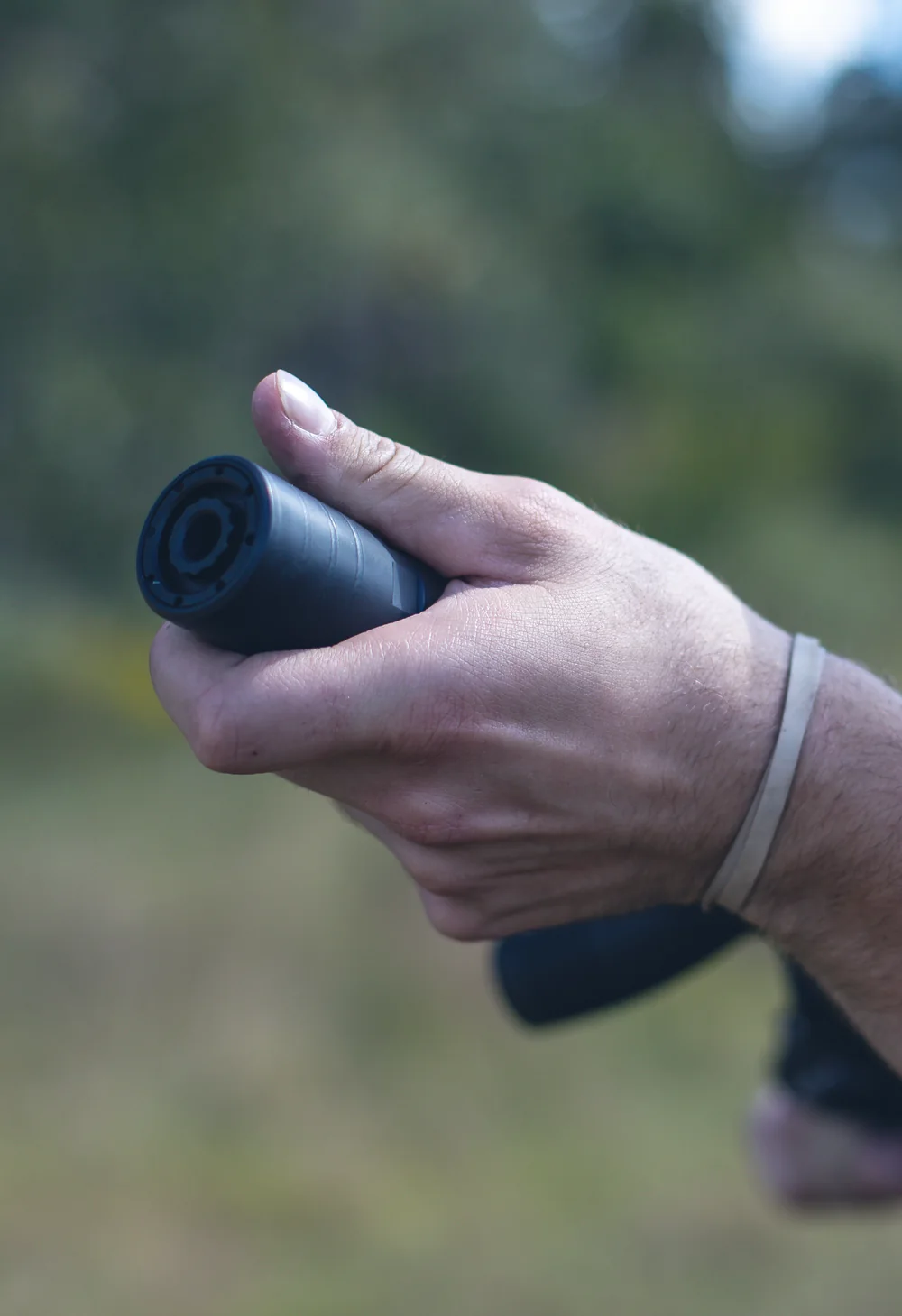 Calloused hand gripping a suppressor, endcap machining to camera